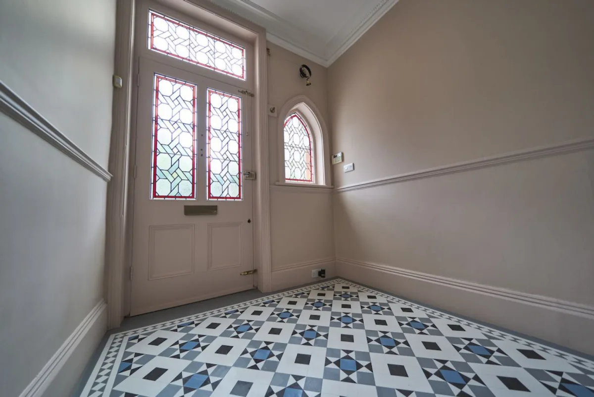 The Crescent Road hallway after: restored walls and woodwork framing the stained-glass entrance and tiled floor