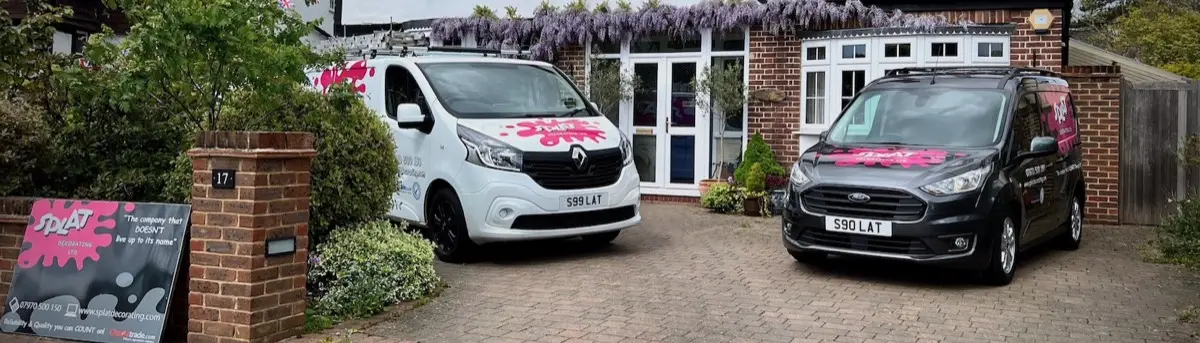 Two Splat Decorating vans parked outside a house with wisteria