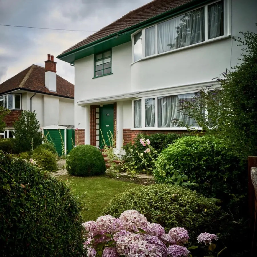 1930s house with freshly painted white render, green windows and front door