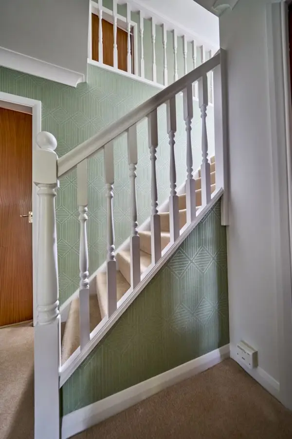 Staircase and hallway with new green wallpaper and white spindles
